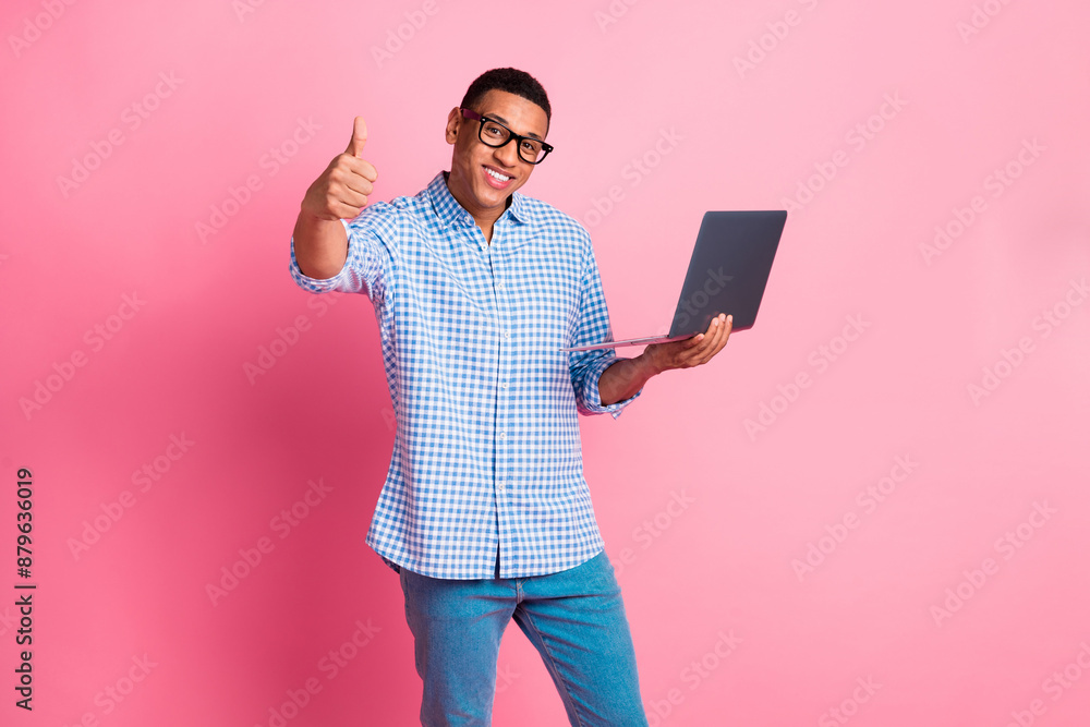 Photo of cheerful positive guy dressed checkered shirt working modern device showing thumb up isolated pink color background Photo of cheerful positive guy dressed checkered shirt working modern device showing thumb up isolated pink color background