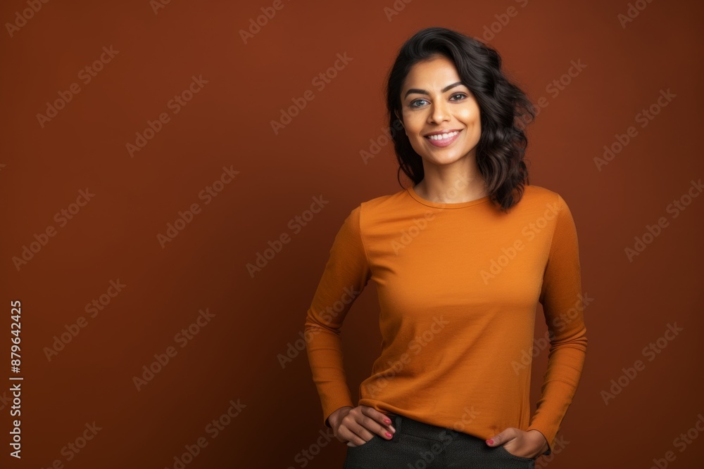Obraz premium Portrait of a satisfied indian woman in her 20s showing off a thermal merino wool top on solid color backdrop
