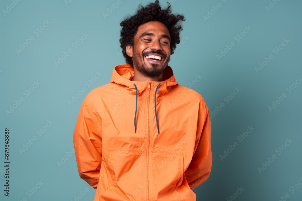 Portrait of a blissful indian man in his 20s wearing a functional windbreaker isolated on solid color backdrop Portrait of a blissful indian man in his 20s wearing a functional windbreaker isolated on solid color backdrop