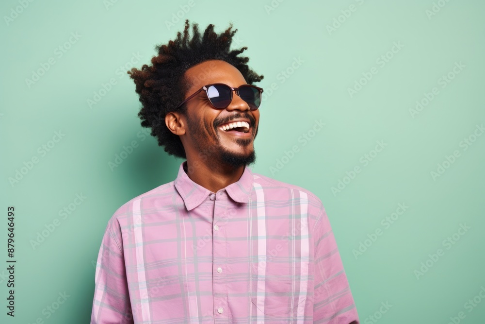 Portrait of a jovial afro-american man in his 30s dressed in a relaxed flannel shirt isolated in solid pastel color wall Portrait of a jovial afro-american man in his 30s dressed in a relaxed flannel shirt isolated in solid pastel color wall
