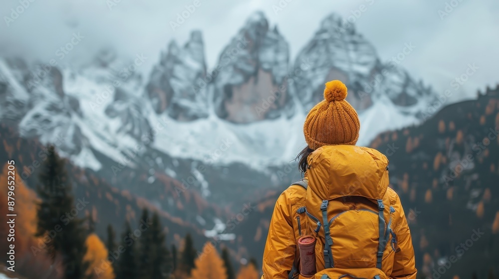 A hiker in an orange outfit stands before majestic, snow-capped peaks, surrounded by an autumnal landscape and trees, capturing the essence of adventure and nature. A hiker in an orange outfit stands before majestic, snow-capped peaks, surrounded by an autumnal landscape and trees, capturing the essence of adventure and nature.