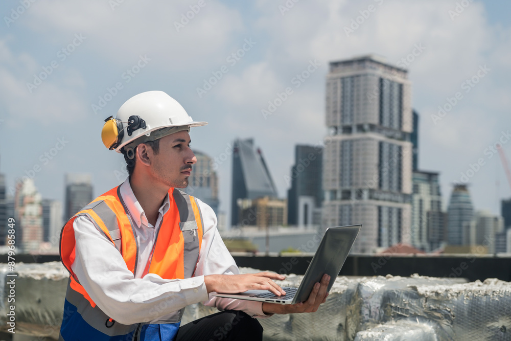 A male engineer works with communications on the roof of a tall building with surrounding engineering systems. A male engineer works with communications on the roof of a tall building with surrounding engineering systems.