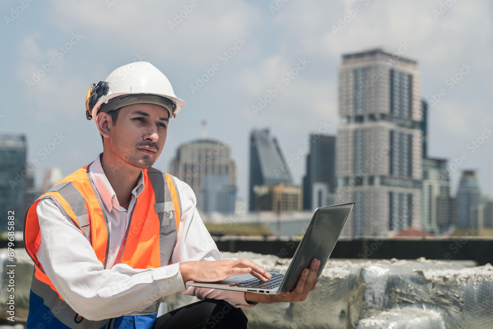 A male engineer works with communications on the roof of a tall building with surrounding engineering systems. A male engineer works with communications on the roof of a tall building with surrounding engineering systems.