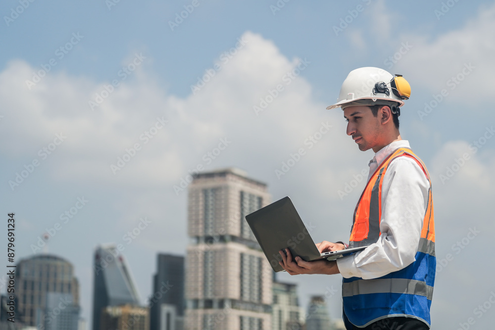 A male engineer works with communications on the roof of a tall building with surrounding engineering systems. A male engineer works with communications on the roof of a tall building with surrounding engineering systems.