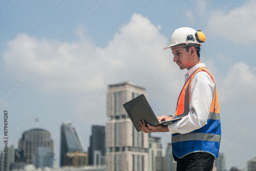 A male engineer works with communications on the roof of a tall building with surrounding engineering systems. A male engineer works with communications on the roof of a tall building with surrounding engineering systems.