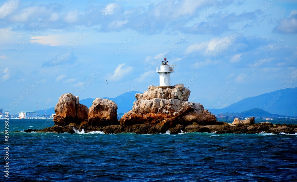 white lighthouse on a rock in the middle of the ocean. Dark blue water white lighthouse on a rock in the middle of the ocean. Dark blue water