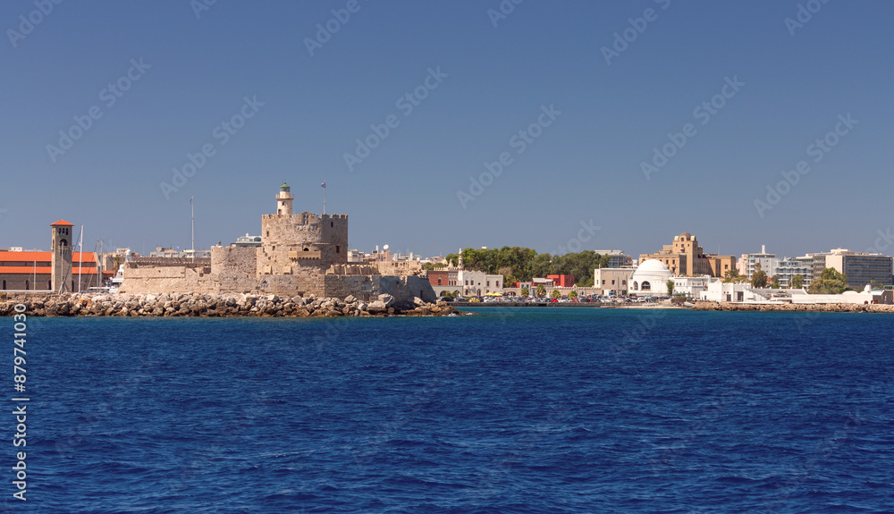 Old stone lighthouse illuminated by the sun at Fort St. Nicholas in Rhodes. Old stone lighthouse illuminated by the sun at Fort St. Nicholas in Rhodes.