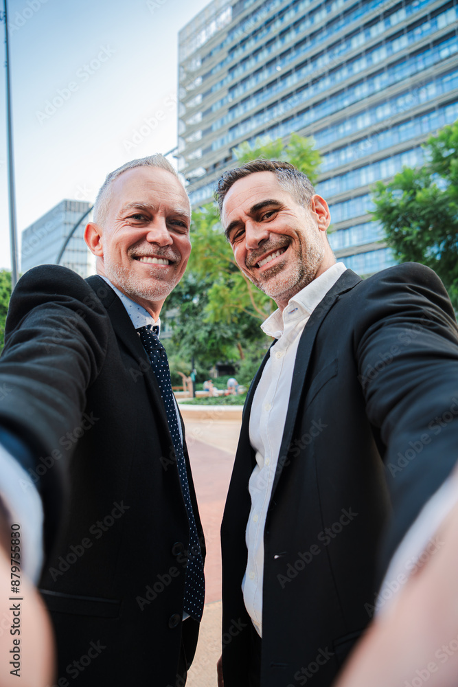 Vertical. Two mature well dressed business men taking a selfie portrait with a friendly expression. Corporate partners, lawyers, agents, finance salesmen, accountants or managers looking at camera Vertical. Two mature well dressed business men taking a selfie portrait with a friendly expression. Corporate partners, lawyers, agents, finance salesmen, accountants or managers looking at camera