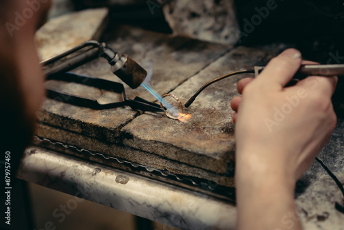 Tablou pe pânză Close-up of a hand of a goldsmith who builds a precious jewel with valuable diamonds