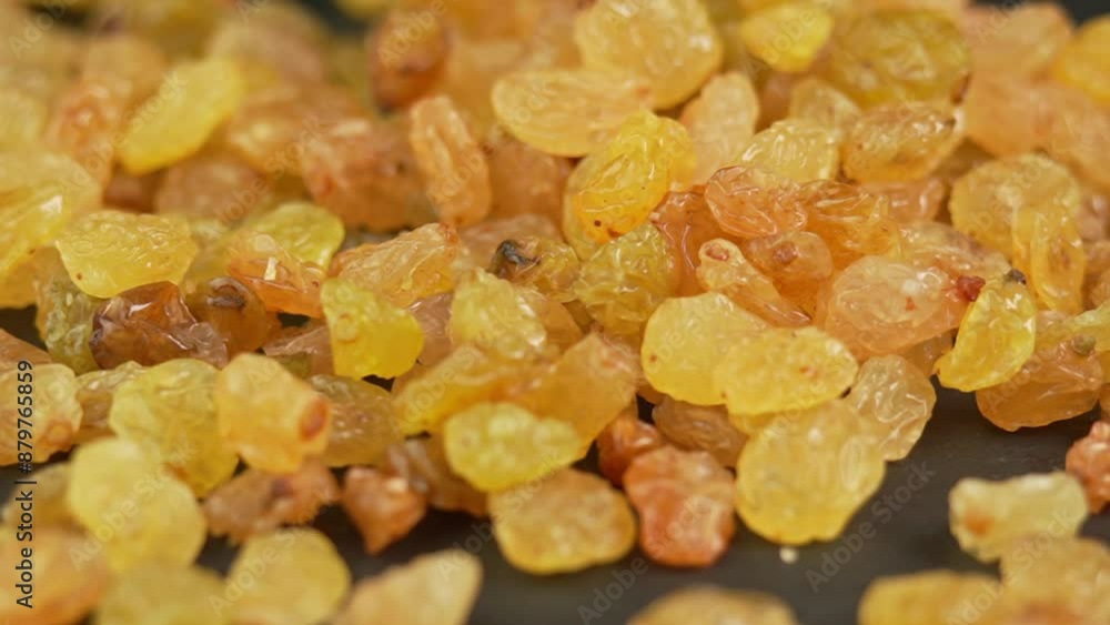 Green raisins slowly pouring onto black plate in slow motion. Dried fruits and dry berries. Dried grapes close up Green raisins slowly pouring onto black plate in slow motion. Dried fruits and dry berries. Dried grapes close up