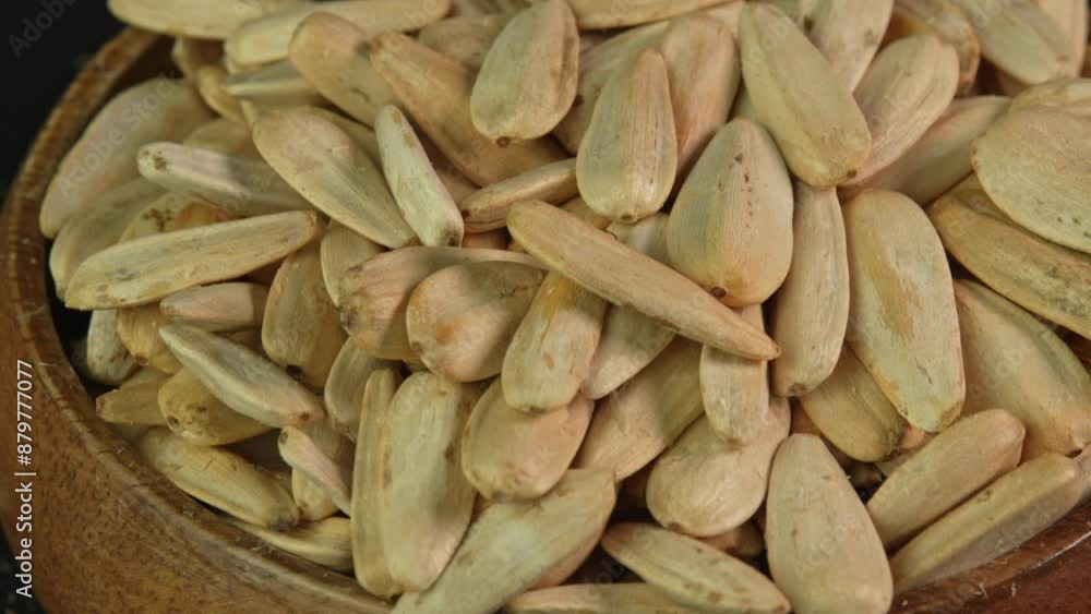 White sunflower seeds rotate in wooden bowl in macro. Turkish variety of sunflower seeds close up. Snacks for snacking or watching movies White sunflower seeds rotate in wooden bowl in macro. Turkish variety of sunflower seeds close up. Snacks for snacking or watching movies