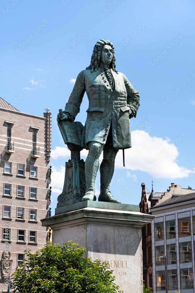 Obraz premium Side view of the Georg Friedrich Händel monument on the market square in Halle Saale. In the background the Halle town hall with the city coat of arms. The city's most famous person. Baroque musician.