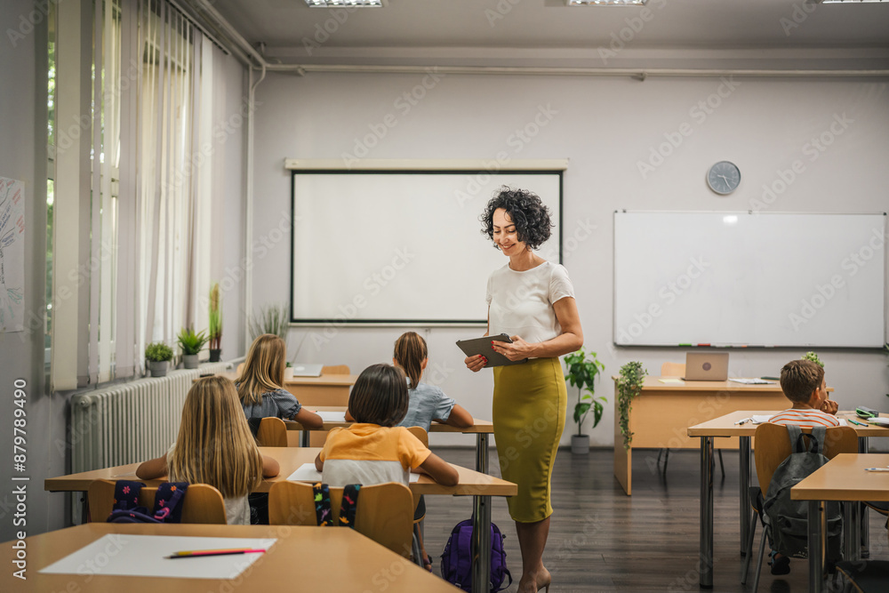 Mature teacher hold tablet and check how her students learn lesson Mature teacher hold tablet and check how her students learn lesson