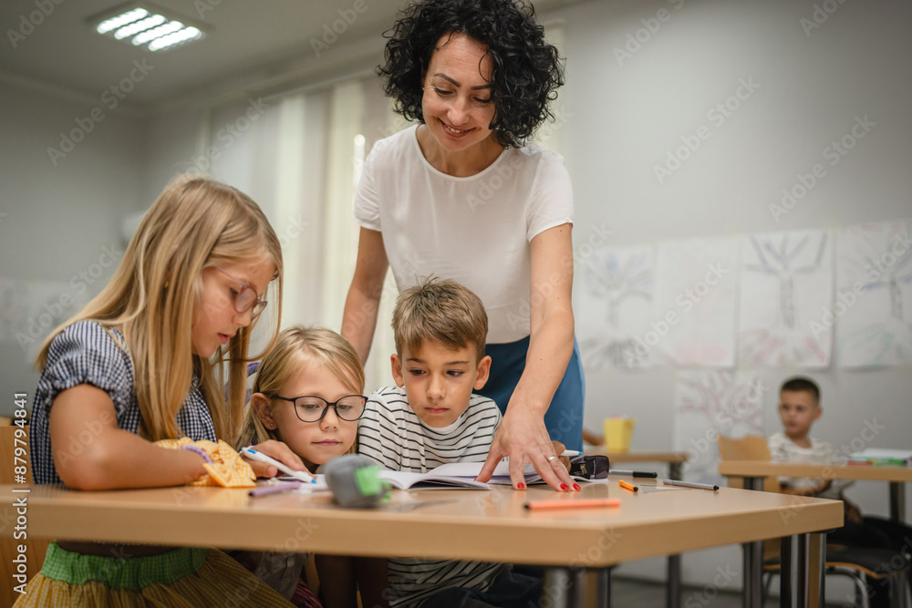 Mature teacher check how her young students do tasks on the class Mature teacher check how her young students do tasks on the class