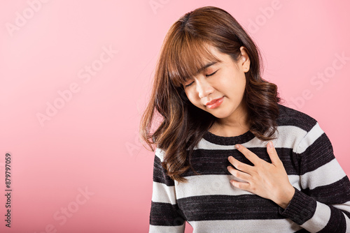 Young woman pressing on chest pain isolated on pink background, painful expression heartache, female having heart attack heart disease, Painful cramps