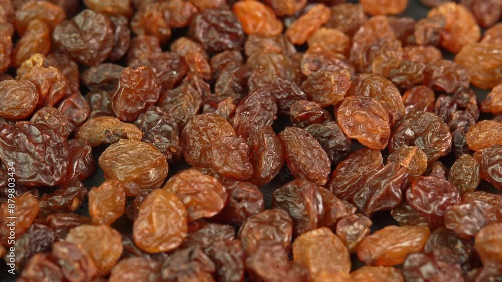 Black raisins slowly rotating in macro background. Dried grapes close up. Dried fruits and dry berries Black raisins slowly rotating in macro background. Dried grapes close up. Dried fruits and dry berries
