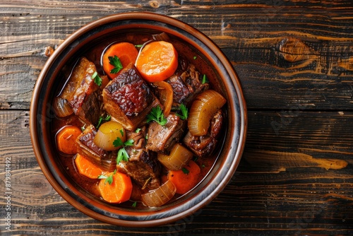 Pork cheeks with carrots and celeriac in sauce on wooden surface photo