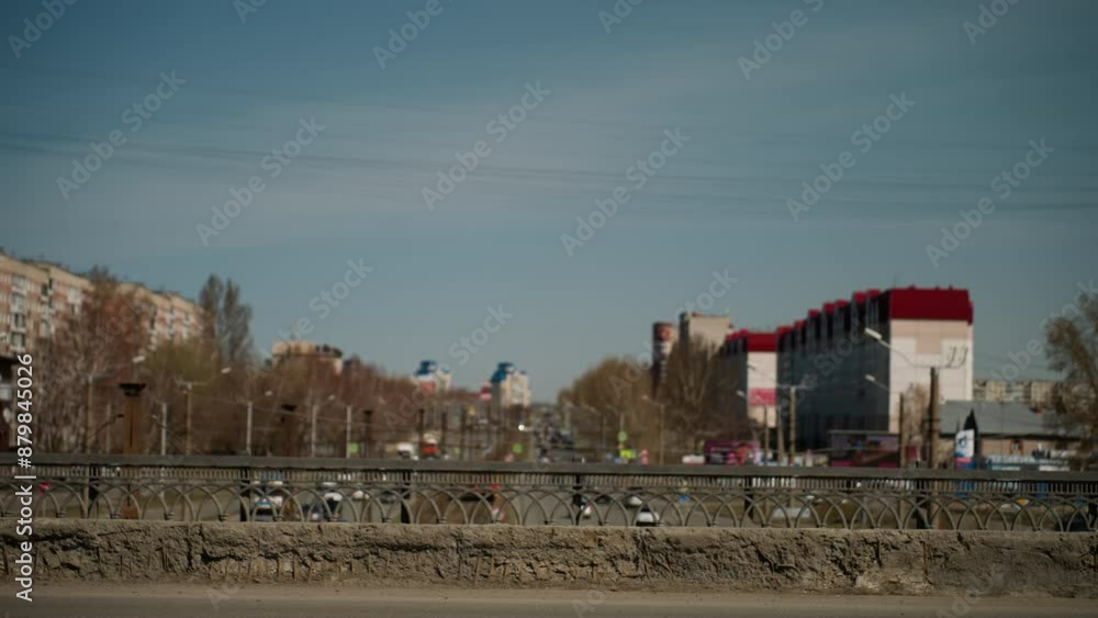 Close view of an urban cityscape featuring distant buildings and a busy road with moving vehicles on the bridge and under the bridge Close view of an urban cityscape featuring distant buildings and a busy road with moving vehicles on the bridge and under the bridge