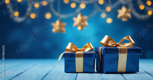 Two elegant blue gift boxes with gold ribbons on a blue bokeh background, perfect for holiday or special occasion marketing, social media posts, or greeting cards.