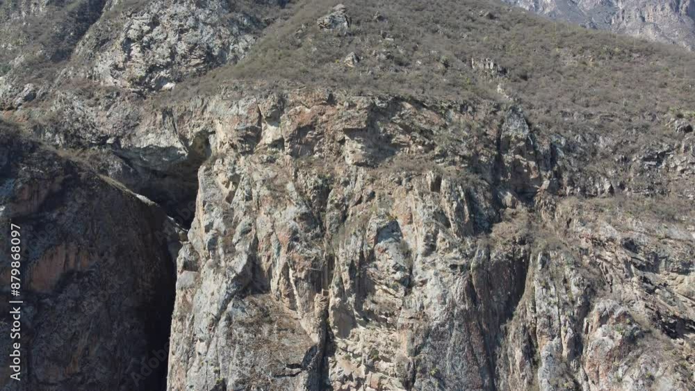 Aerial view of rugged mountain terrain in remote canyon with steep cliffs and sparse vegetation Aerial view of rugged mountain terrain in remote canyon with steep cliffs and sparse vegetation