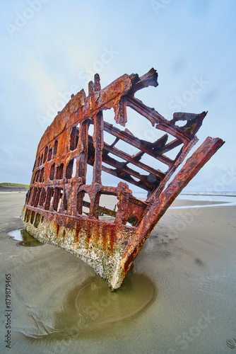 Rusted Shipwreck on Sandy Beach with Low Angle Perspective photo