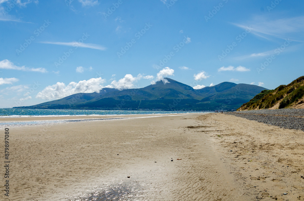 View of the Mourne Mountains from Murlough beach with blue sky and wispy clouds View of the Mourne Mountains from Murlough beach with blue sky and wispy clouds