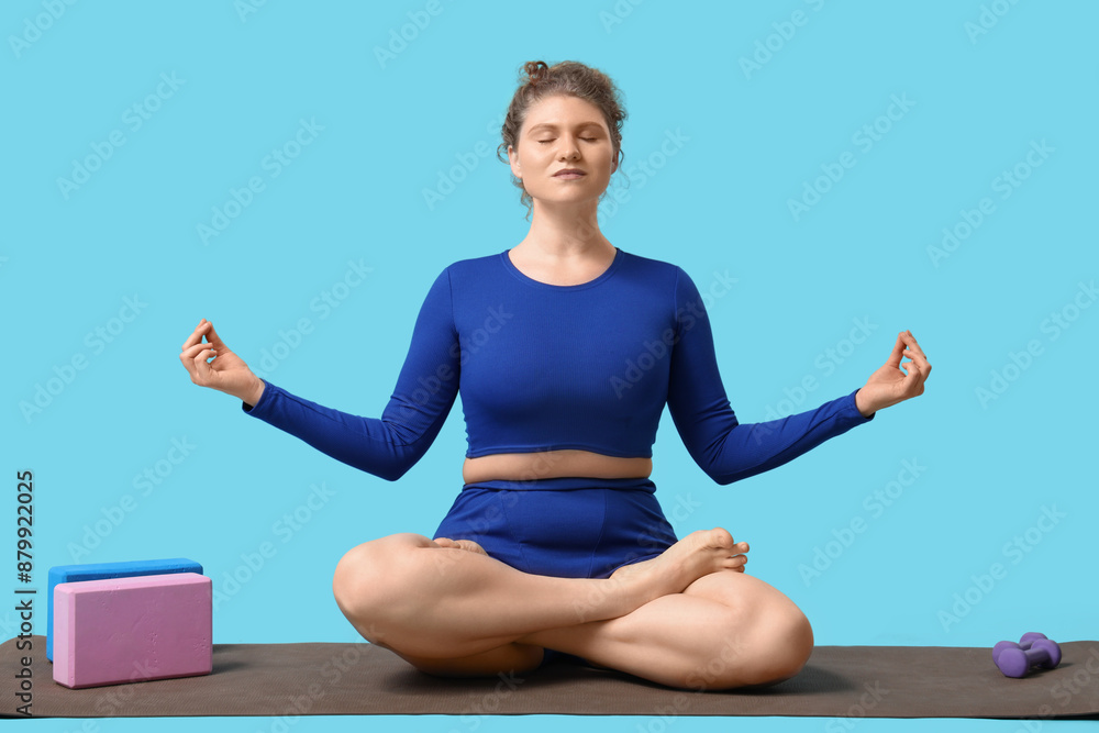 Meditating young woman doing yoga on blue background Meditating young woman doing yoga on blue background