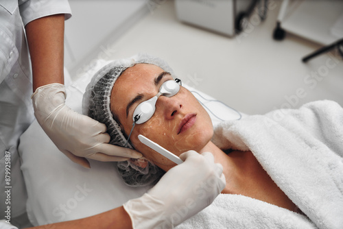 A woman applies gel to her face before a laser procedure.