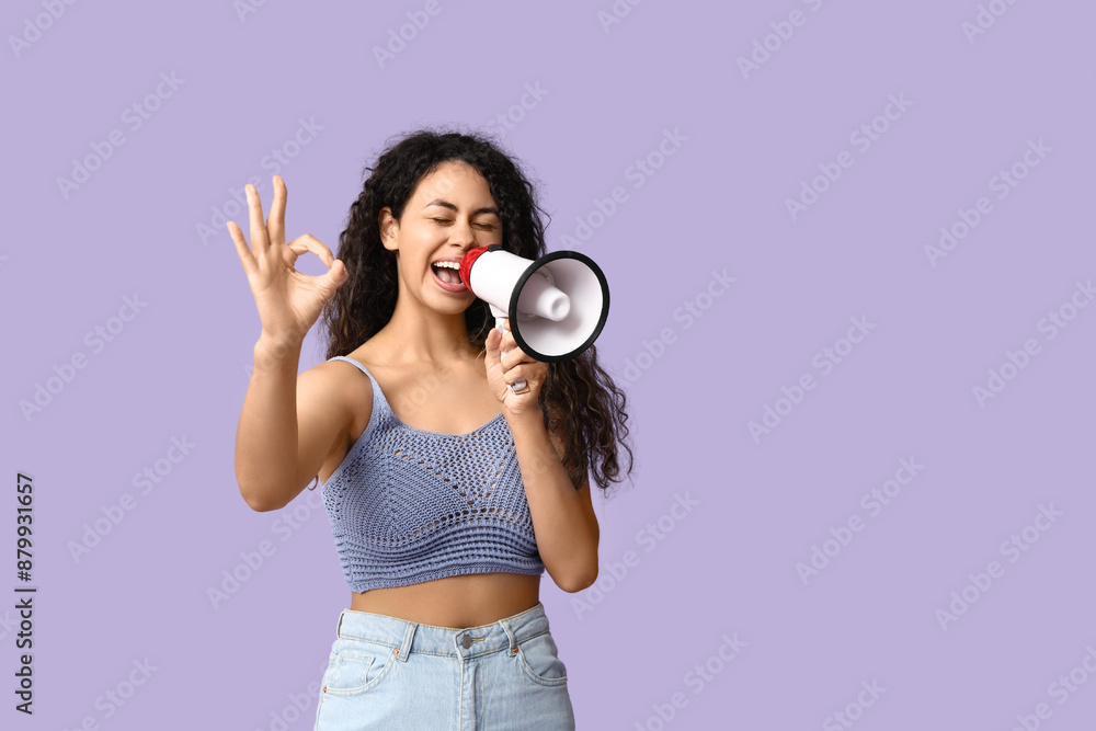 Young African-American woman with megaphone showing OK on lilac background Young African-American woman with megaphone showing OK on lilac background