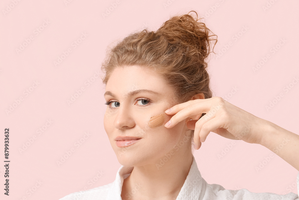 Beautiful young woman with makeup foundation on her face against pink background Beautiful young woman with makeup foundation on her face against pink background