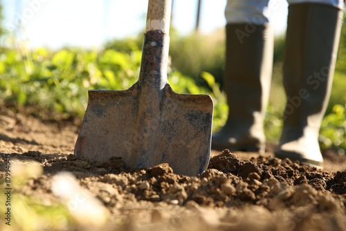 Farmer digging soil with shovel on sunny day, closeup