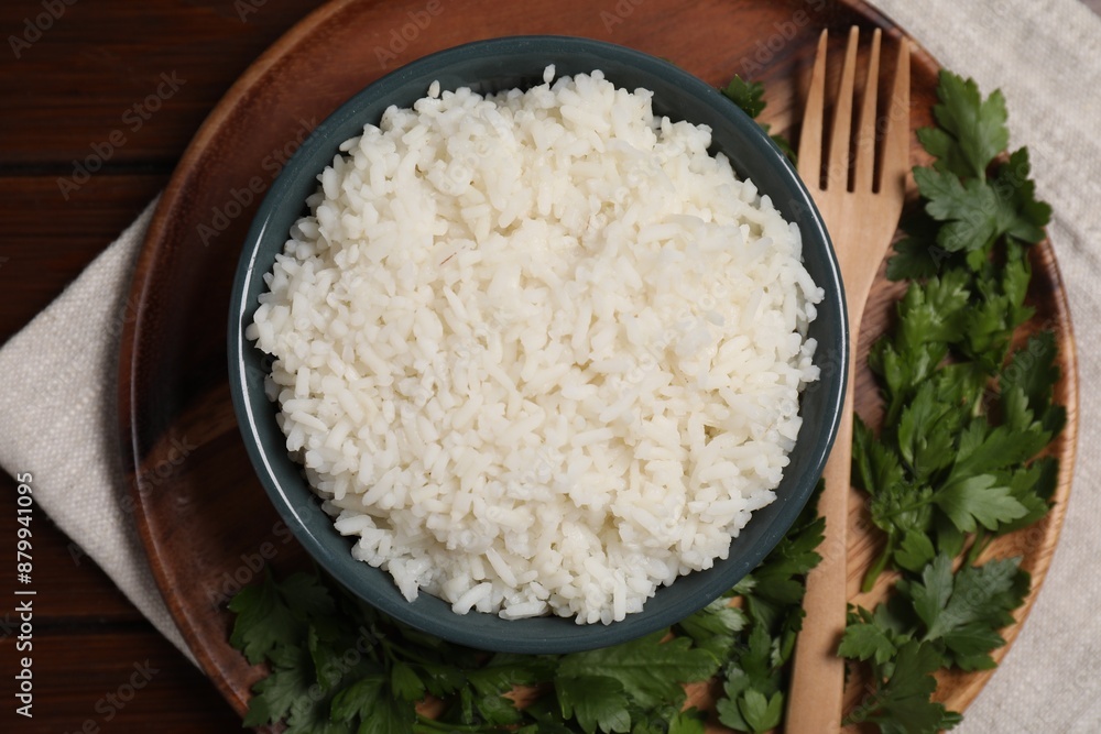 Delicious boiled rice served with parsley on wooden table, top view Delicious boiled rice served with parsley on wooden table, top view