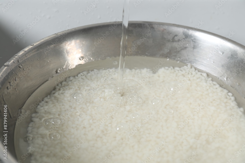 Pouring water into bowl with rice in sink, closeup Pouring water into bowl with rice in sink, closeup