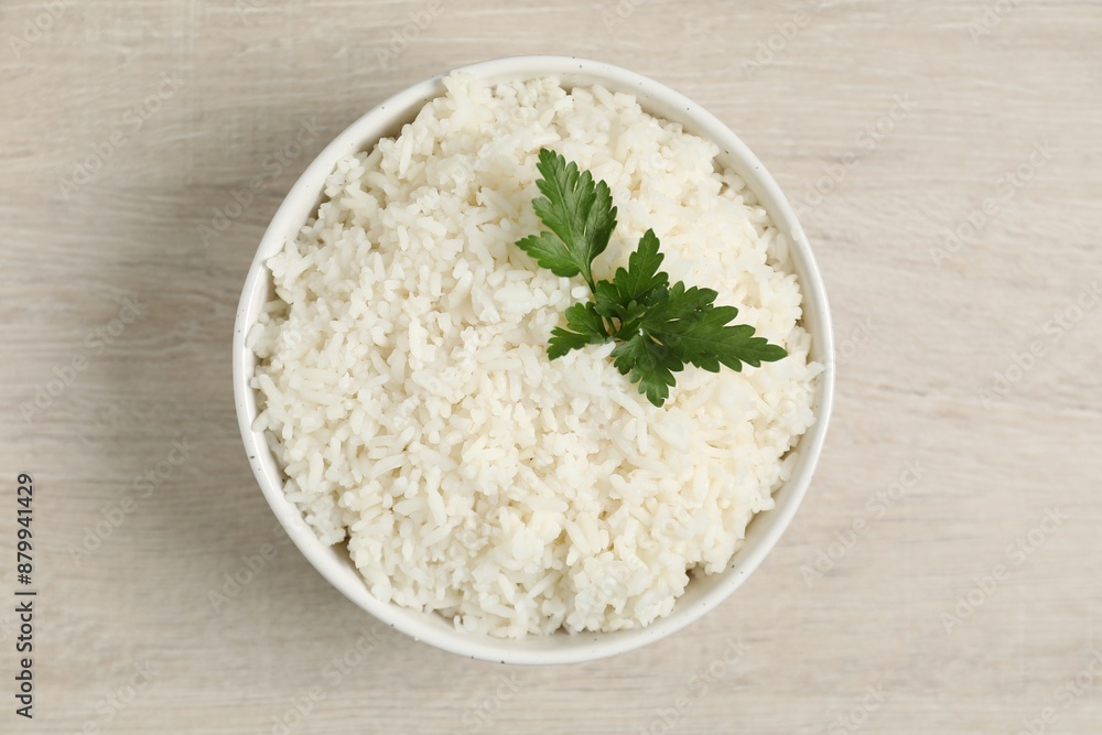 Delicious boiled rice in bowl and parsley on wooden table, top view Delicious boiled rice in bowl and parsley on wooden table, top view