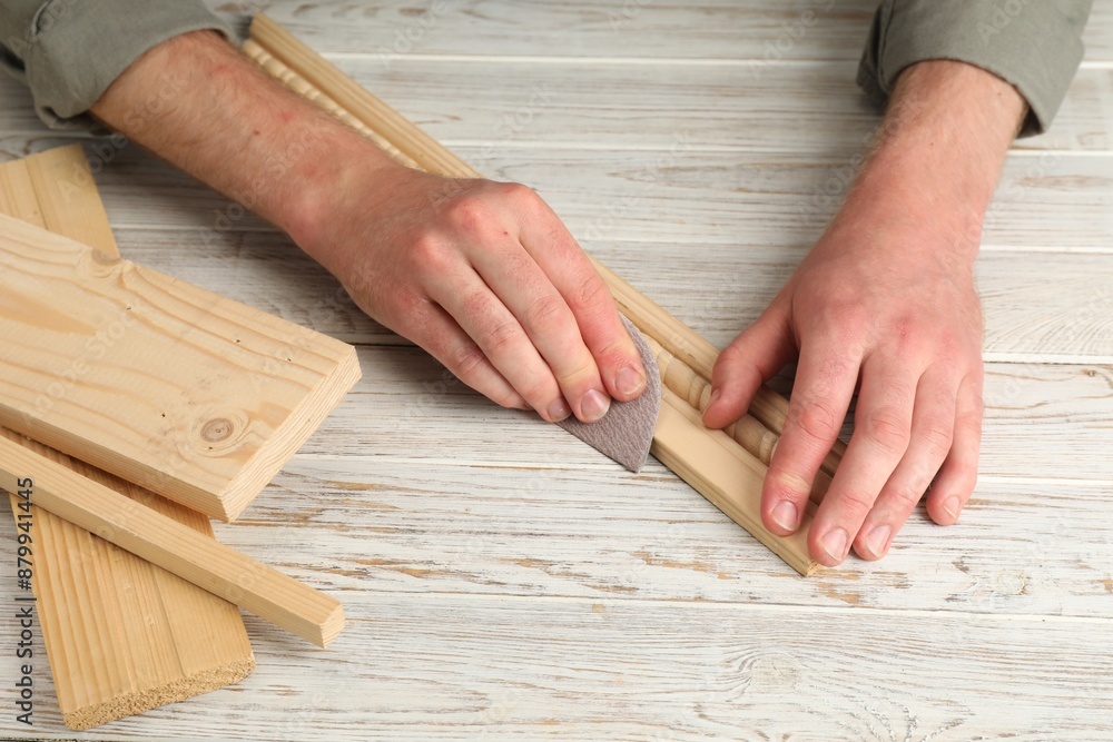Man polishing wooden plank with sandpaper at table, closeup Man polishing wooden plank with sandpaper at table, closeup