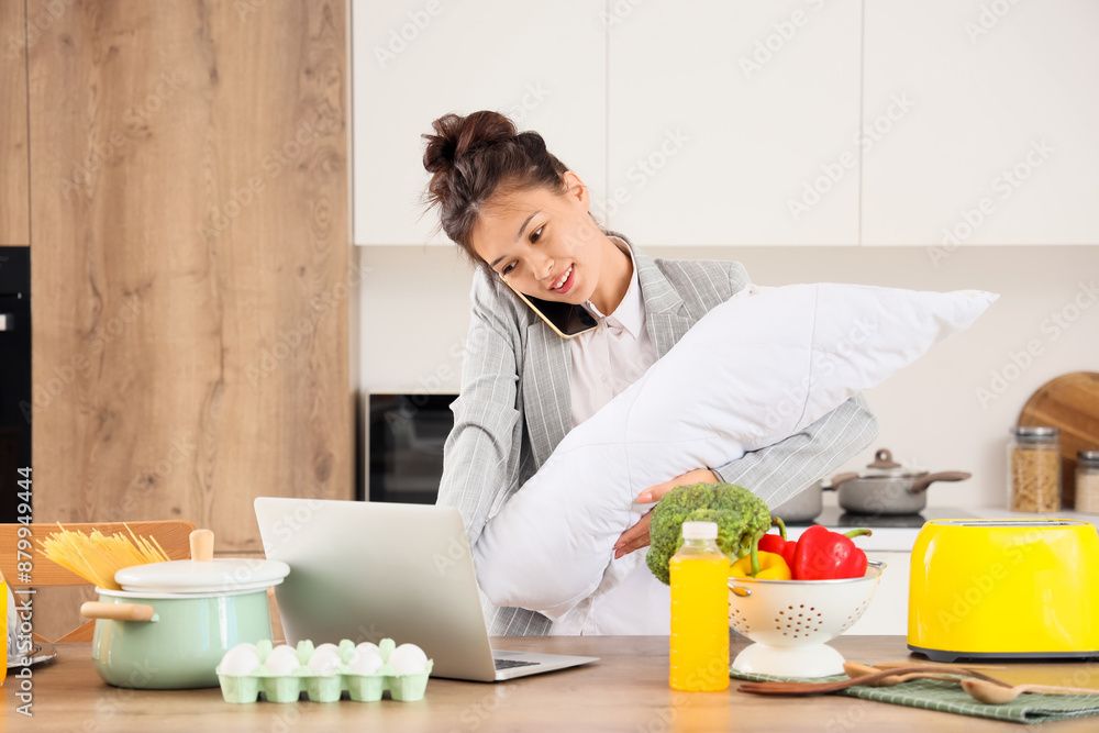 Φωτογραφία Overwhelmed Asian mother in suit with baby, laptop and mobile phone working while cooking at home
