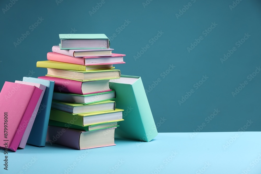 Stack of colorful books on light blue background, space for text Stack of colorful books on light blue background, space for text