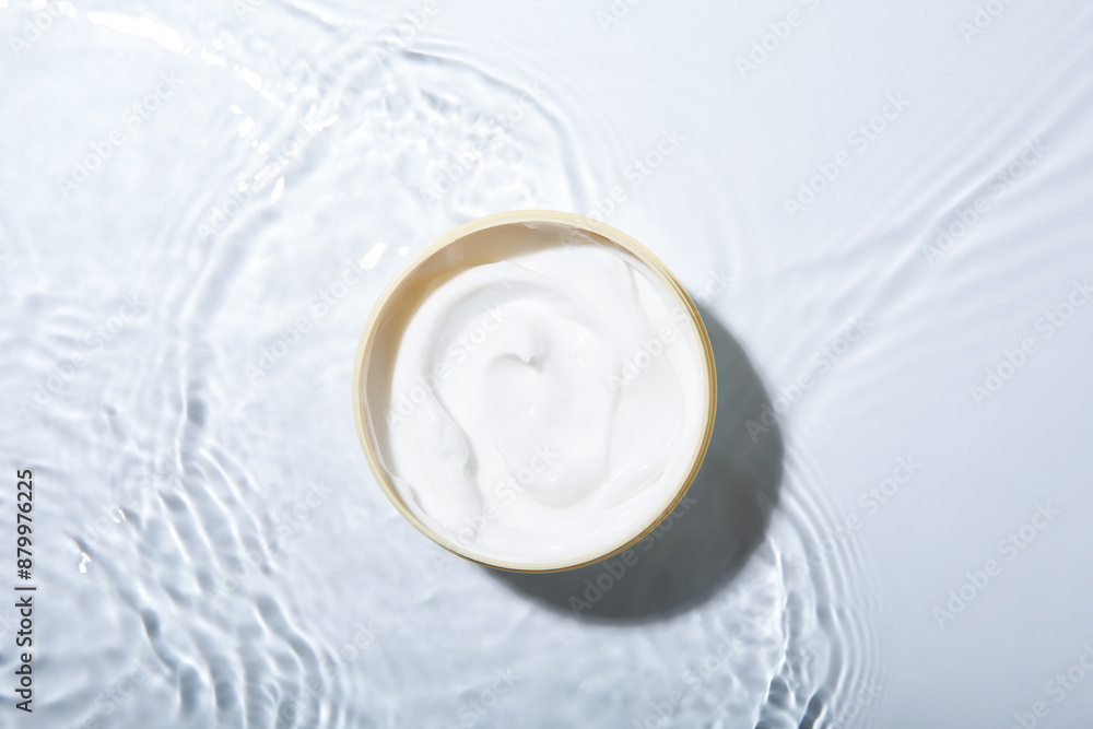 Cosmetic product. Jar with cream in water on light background, top view Cosmetic product. Jar with cream in water on light background, top view