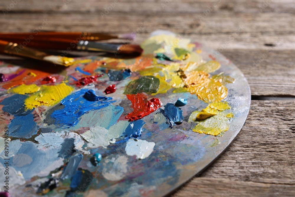 Obraz premium Artist's palette, brushes and paints on wooden table, closeup