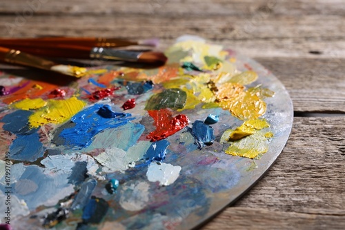 Artist's palette, brushes and paints on wooden table, closeup