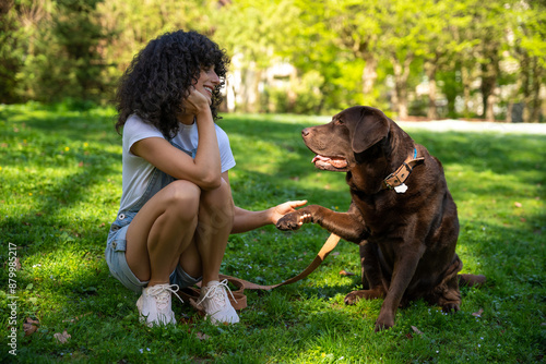 Curly-haired young woman playing with her dog in the park © zinkevych