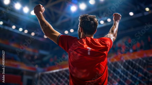 Victorious football player raises hands in the air after winning the football league in the stadium.
Football player determined towards victory. Footballer triumphant pose. Banner, poster