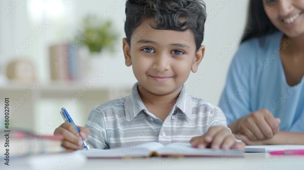 A young boy is sitting at a table with a pen and a book A young boy is sitting at a table with a pen and a book