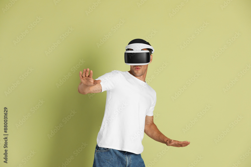 Man using virtual reality headset on light green background Man using virtual reality headset on light green background