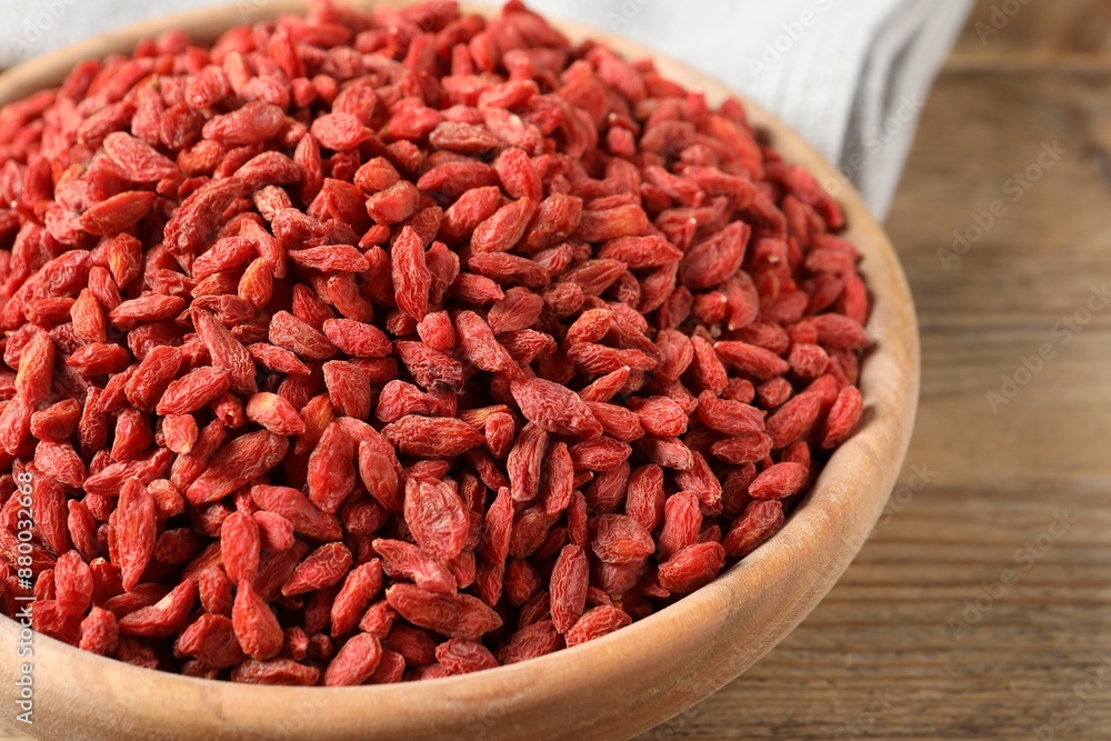 Dried goji berries in bowl on wooden table, closeup Dried goji berries in bowl on wooden table, closeup