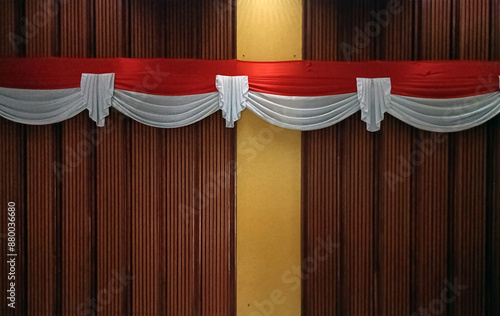 a red and white cloth symbolising the Indonesian flag is stretched across a wooden wall as a room decoration. photo