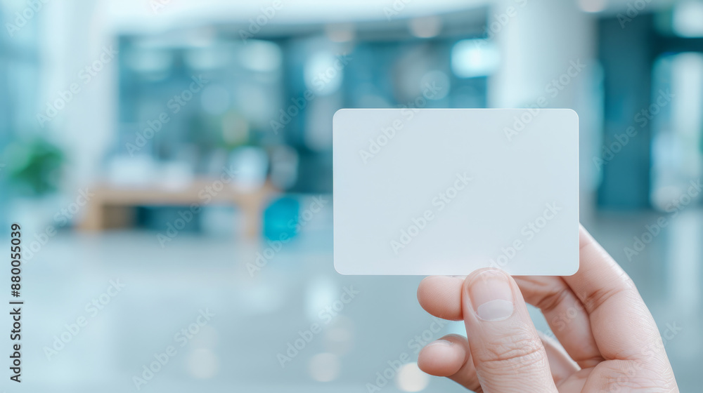 Stylish business card mockup held between fingers with blurred office background Stylish business card mockup held between fingers with blurred office background