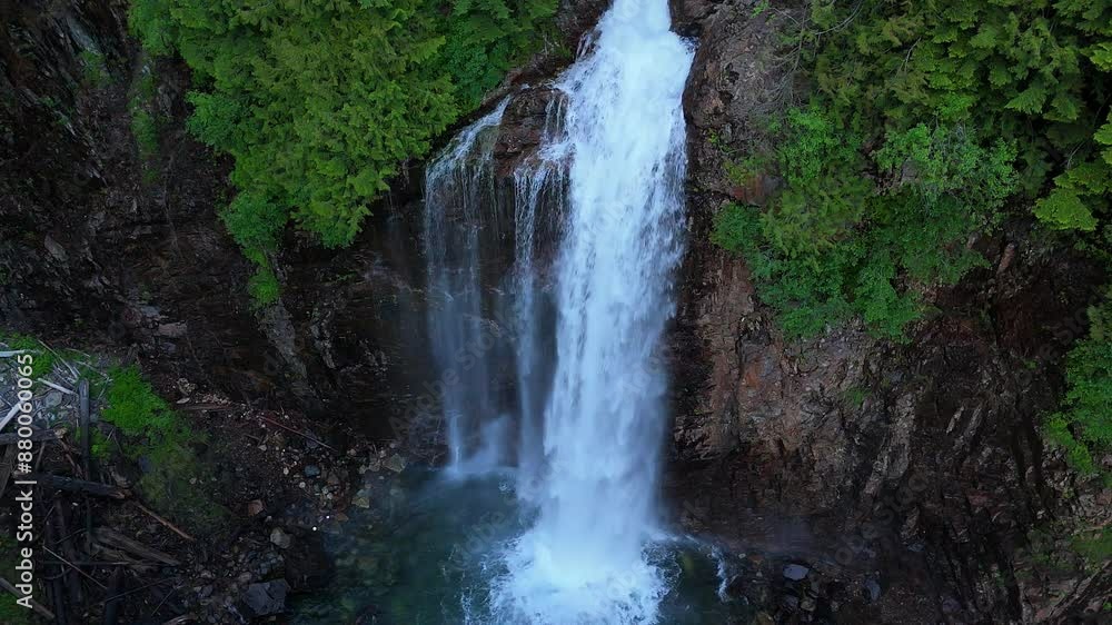 Scenic stationary shot above waterfall flowing off cliff side surrounded by lush green trees in the Pacific Northwest Scenic stationary shot above waterfall flowing off cliff side surrounded by lush green trees in the Pacific Northwest