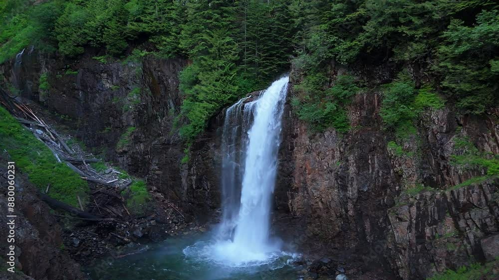 Scenic orbital shot of hidden waterfall cascading down a cliff side in Evergreen Forest in the Pacific Northwest. Scenic orbital shot of hidden waterfall cascading down a cliff side in Evergreen Forest in the Pacific Northwest.