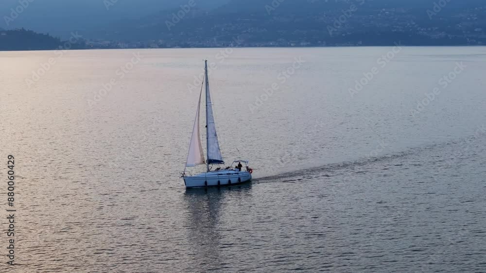 Warm glow on lake water and sailboat sailing across charming Lake Maggiore in Italy. Aeria drone view Warm glow on lake water and sailboat sailing across charming Lake Maggiore in Italy. Aeria drone view